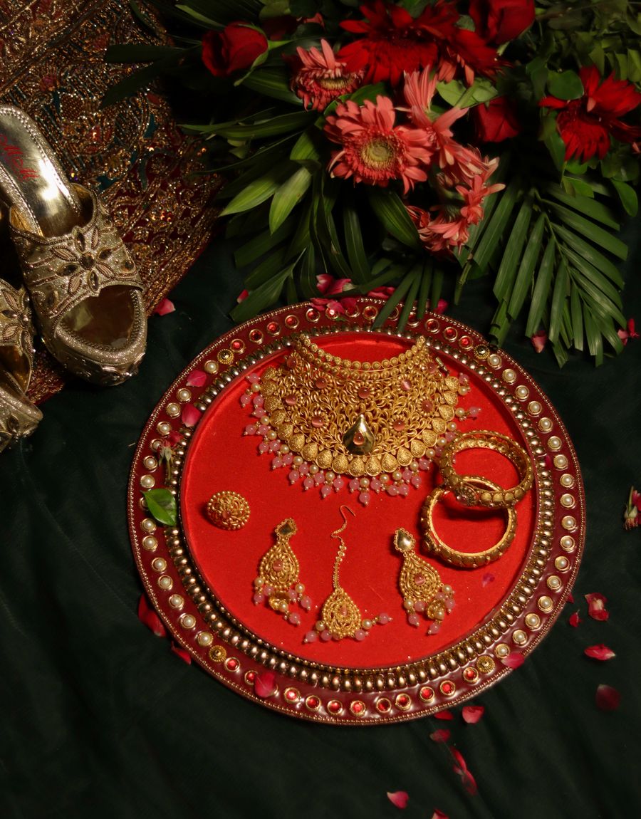 Traditional Indian gold jewellery set displayed on rich red fabric