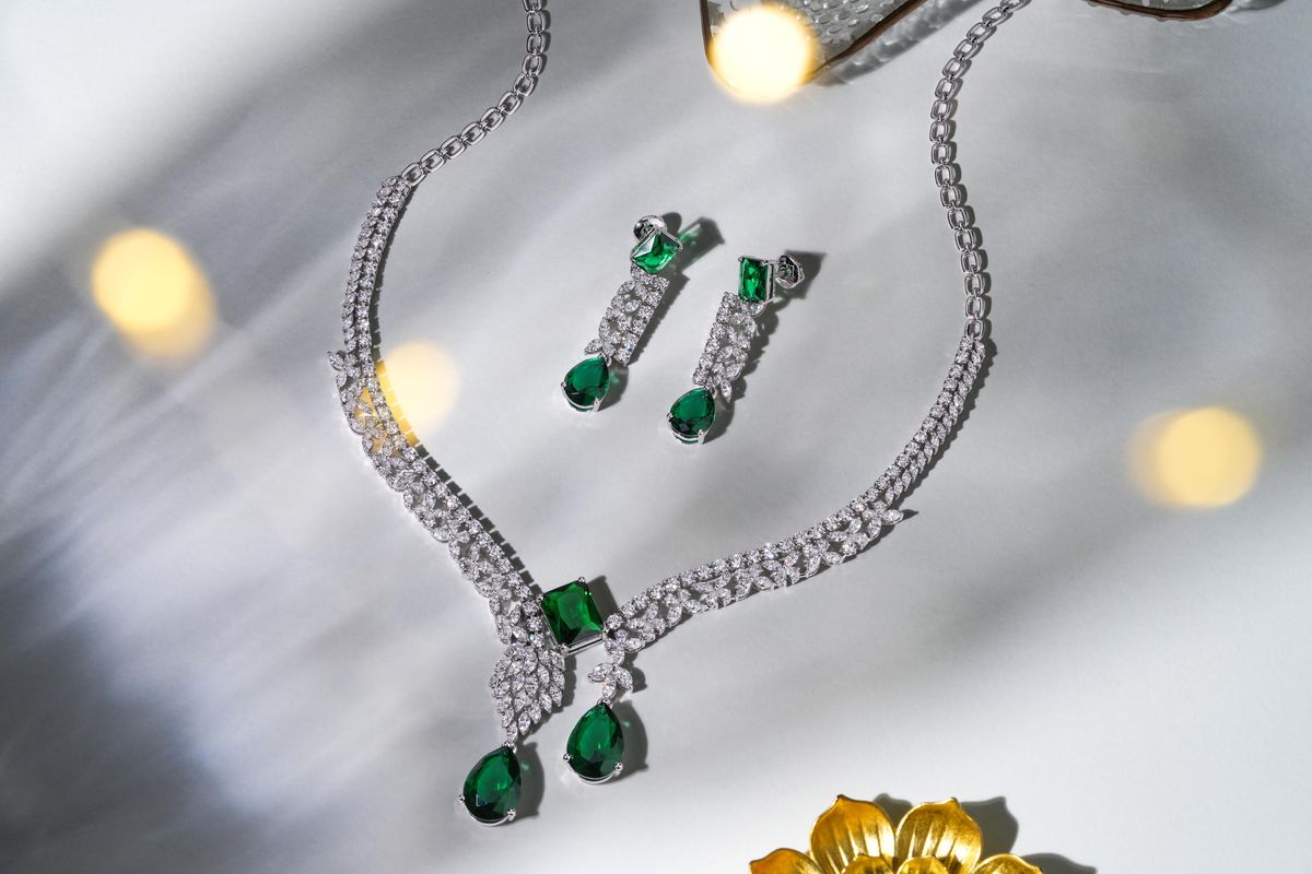 Diamond and emerald necklace set displayed against a festive background