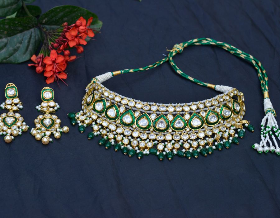Gold necklace and earring set with floral detailing on a blue background
